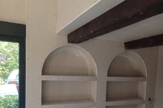 Intérieur en chantier avec deux étagères arquées.