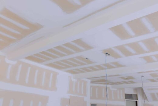 Un plafond et des murs partiellement en placoplâtre avec fils exposés, joints inachevés - en cours.